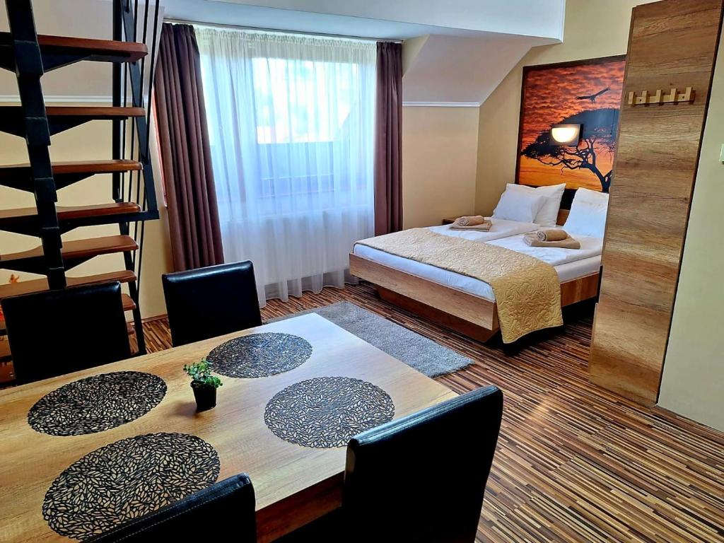 um quarto de hotel com uma cama e uma mesa com cadeiras em Angyal Apartman Gyula em Gyula