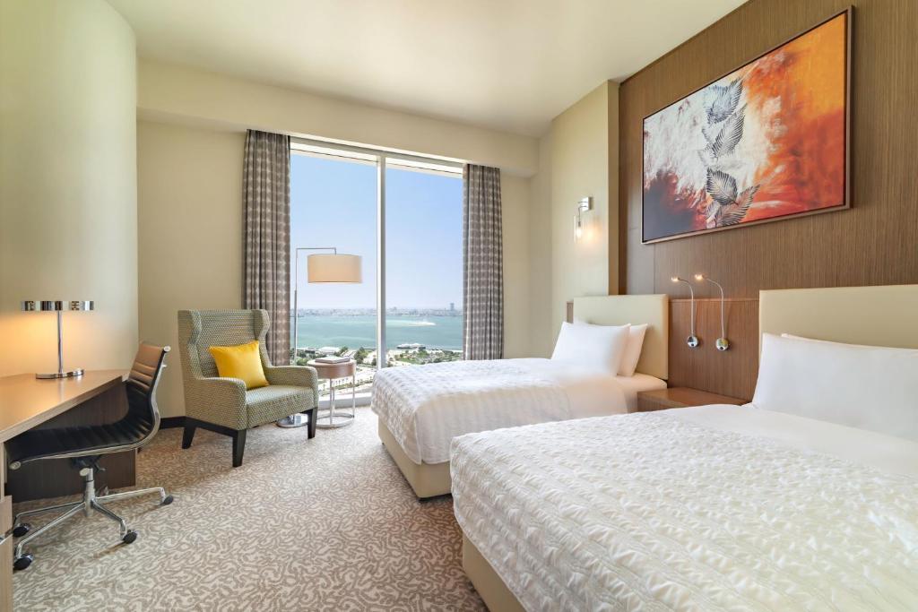 Habitación de hotel con 2 camas y escritorio en Le Méridien City Center Doha en Doha