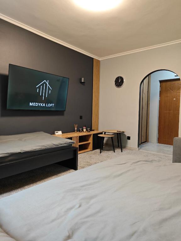 a bedroom with a bed and a television on the wall at Medyka Loft in Medyka