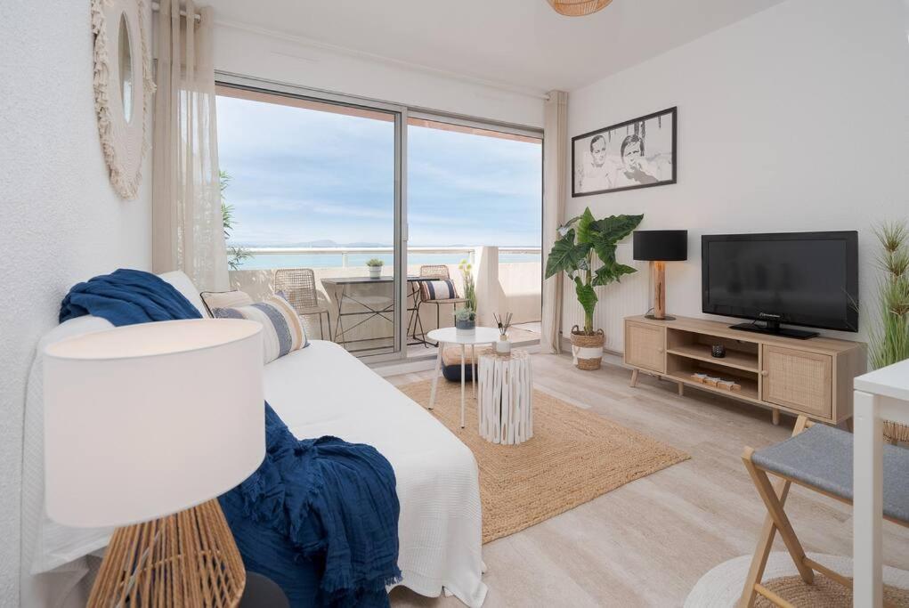 sala de estar con sofá blanco y TV en Superbe appart en bord de mer en Palavas-les-Flots