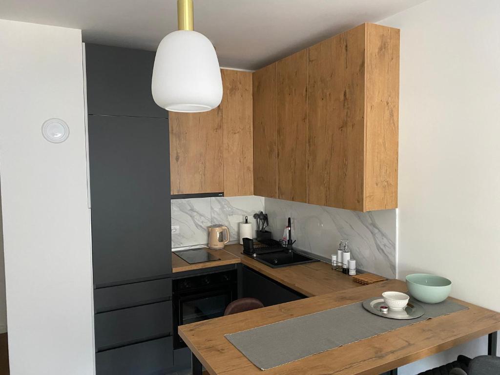 a kitchen with wooden cabinets and a wooden table at Zeus apartman in Hiseti