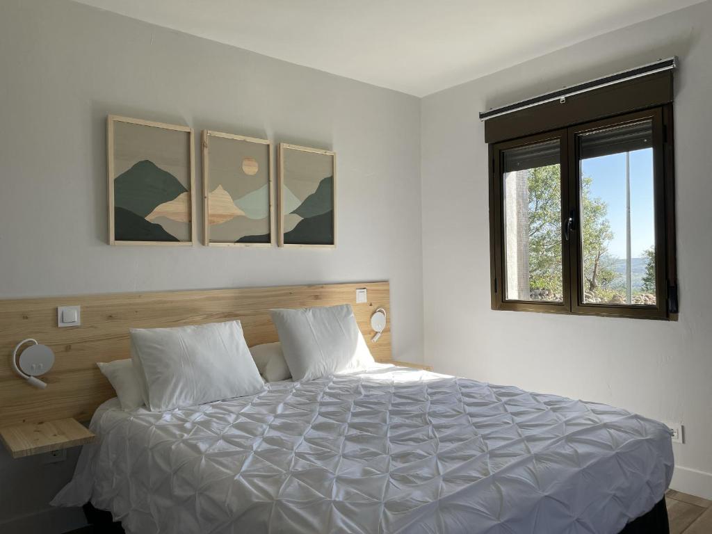1 dormitorio con cama blanca y ventana en Apartamentos Los Pocillos, en Gargantilla del Lozoya
