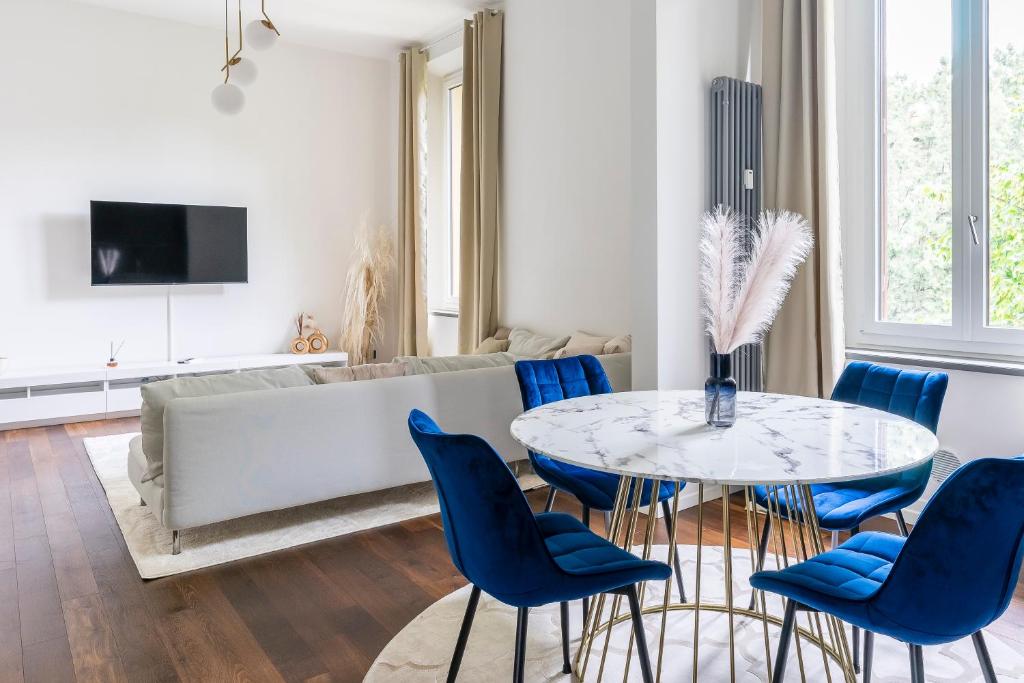 ein Wohnzimmer mit einem Tisch und blauen Stühlen in der Unterkunft San Marco White Appartamento Luxury con Garage su richiesta in Florenz