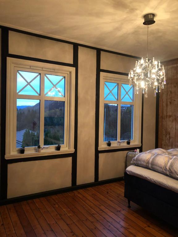 a bedroom with two windows and a chandelier at Villa Henrikke Myhre in Osøyro