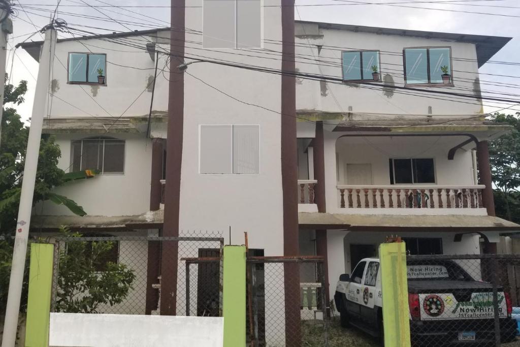 una casa blanca con un coche aparcado delante de ella en Apartamentos JuanSabeloTodo, en Santiago de los Caballeros