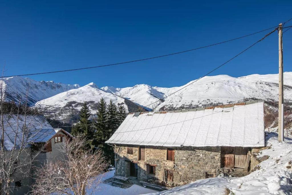 ein altes Gebäude mit schneebedeckten Bergen im Hintergrund in der Unterkunft Chalet Chez Maxime Hameau l’Archaz Valloire in Valloire