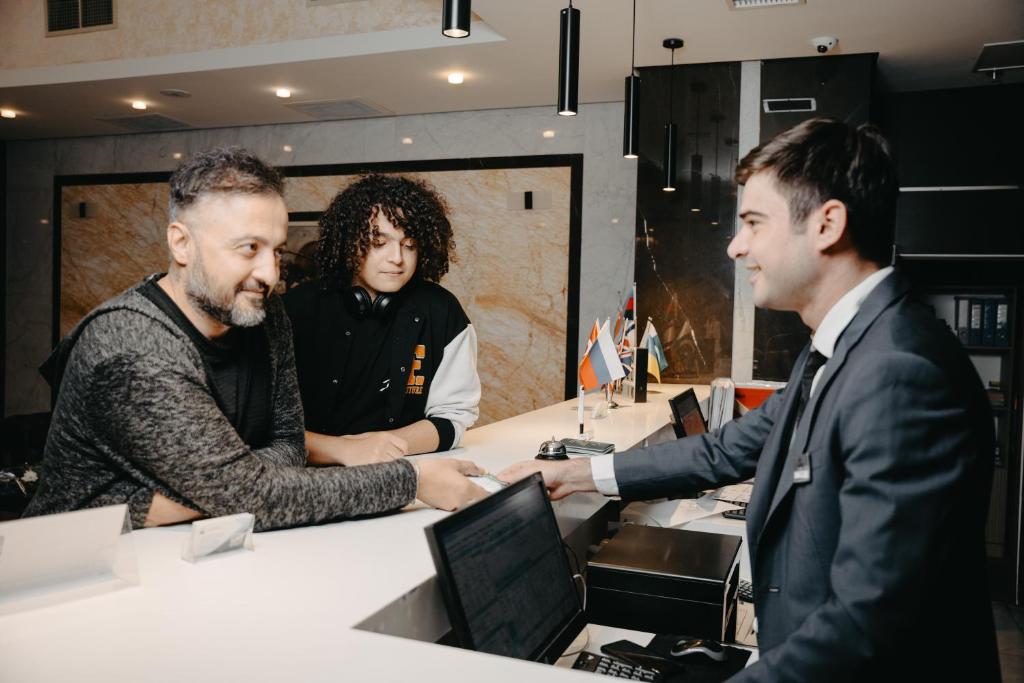 een groep van drie mannen aan een bureau met een computer bij The Diamond Hotel Baku in Baku