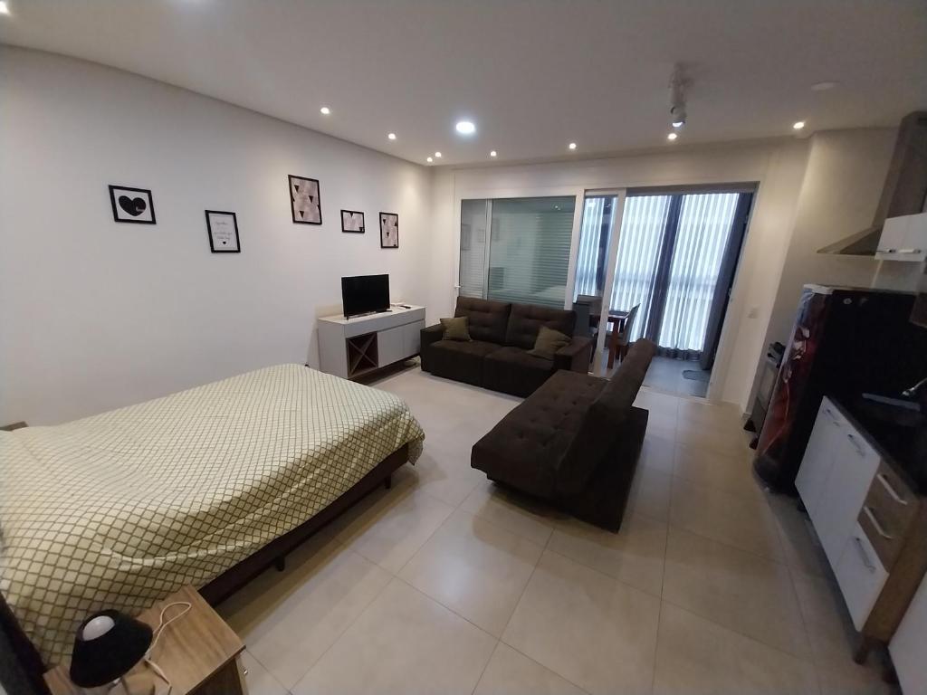 - une chambre avec un lit et un salon avec un canapé dans l'établissement JK STUDIO Xavante com Garagem, à Pelotas