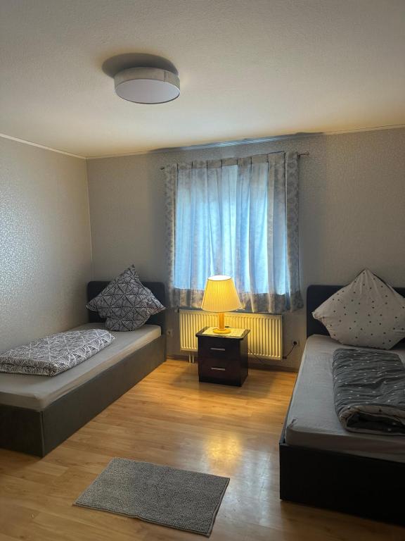 een kamer met 2 bedden, een lamp en een raam bij Zimmer/Wohnung im Zentrum Kehl in Kehl am Rhein