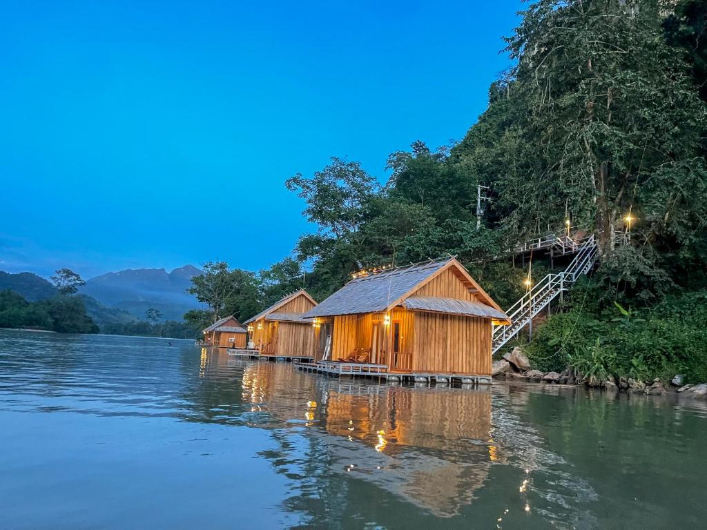uma fila de cabanas de bambu num rio à noite em Nongkhiaw The Float House em Nongkhiaw