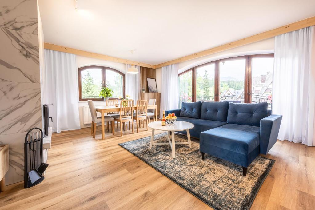 ein Wohnzimmer mit einem blauen Sofa und einem Tisch in der Unterkunft U Majerczyka Polana Apartment in Zakopane