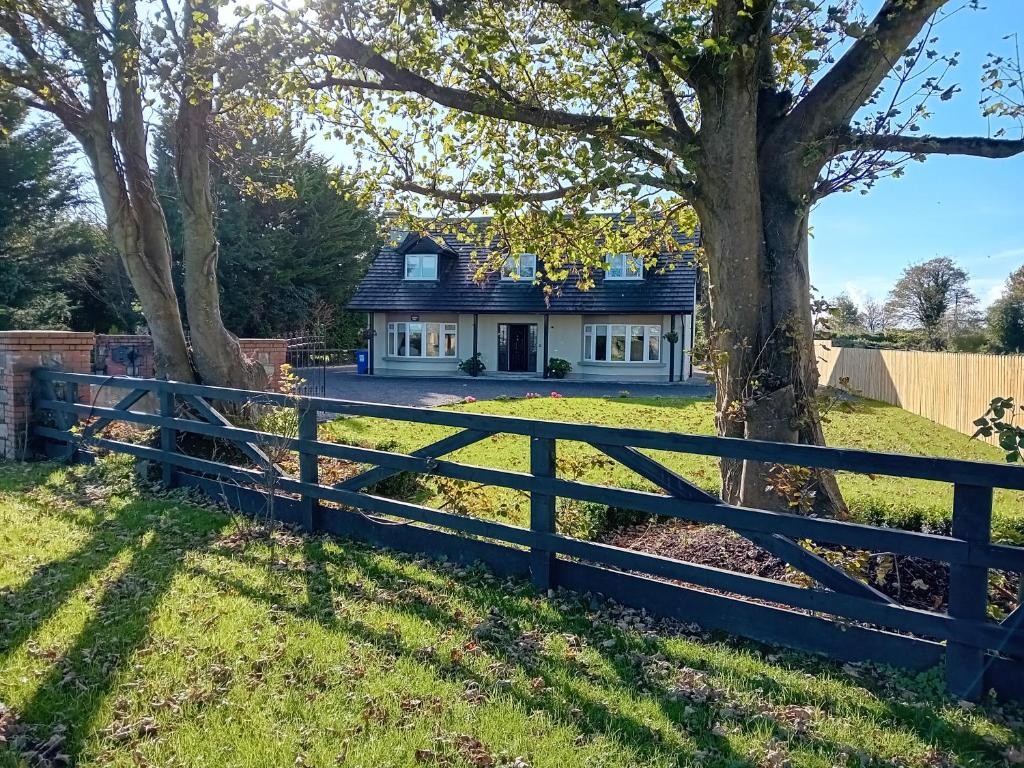 uma casa com uma cerca e uma árvore em White Quarry House em Navan
