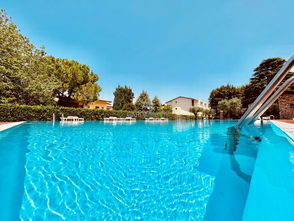 uma grande piscina com água azul em Mercury Apartment - Vista Lago con Piscina em Sirmione
