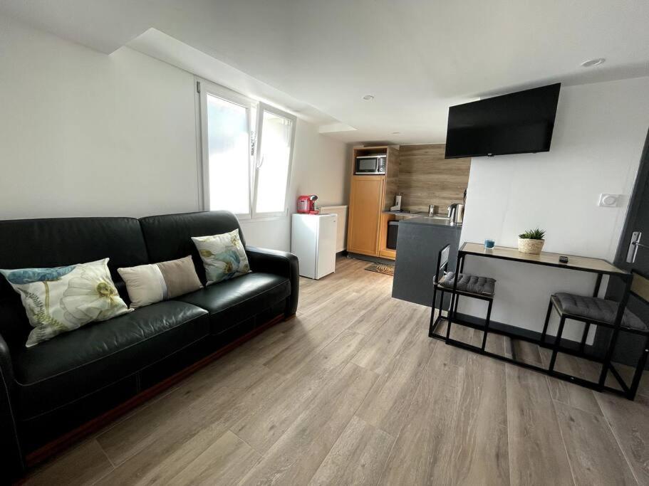 salon z czarną kanapą i kuchnią w obiekcie Douceur Drômoise appartement avec une chambre w mieście Montélimar