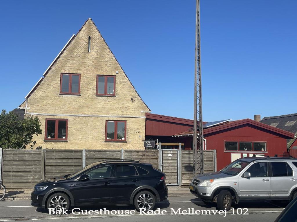 dos autos estacionados en un estacionamiento frente a una casa en Bak Guesthouse en Copenhague