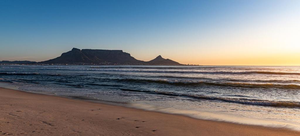 uma praia ao pôr-do-sol com uma montanha ao fundo em Ocean Vibes em Cidade do Cabo