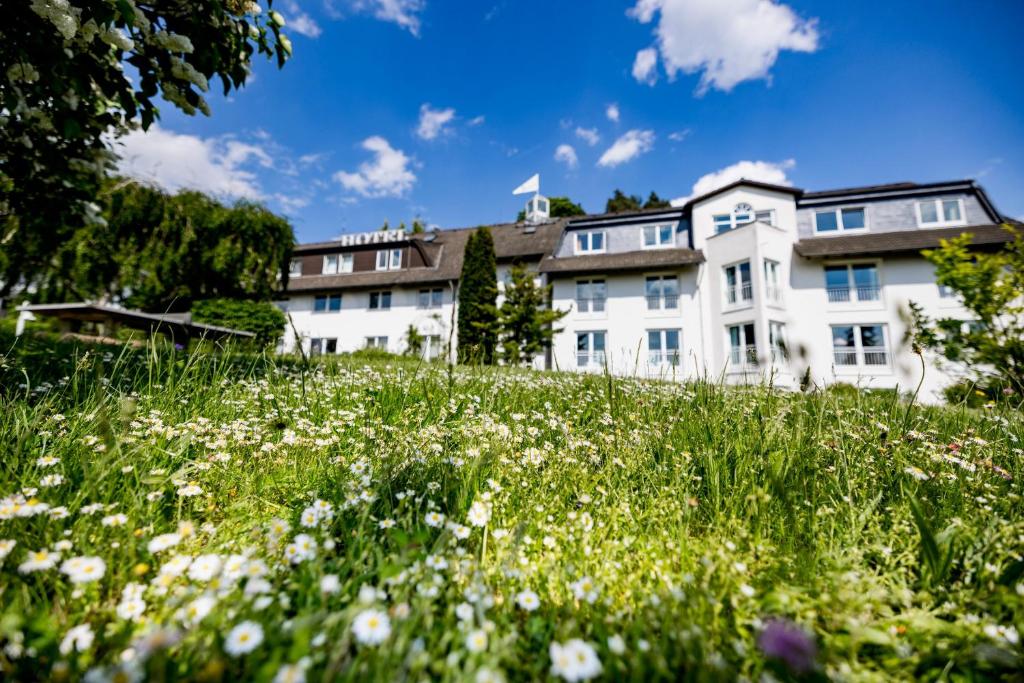 una casa en una colina con un campo de flores en Landhotel Bellevue, en Wolfshausen