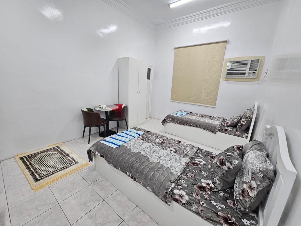 a bedroom with two beds and a table in it at شقة مفرشة رقم 3 تبعد ٣ كم عن الحرم النبوي الشريف in Al Madinah