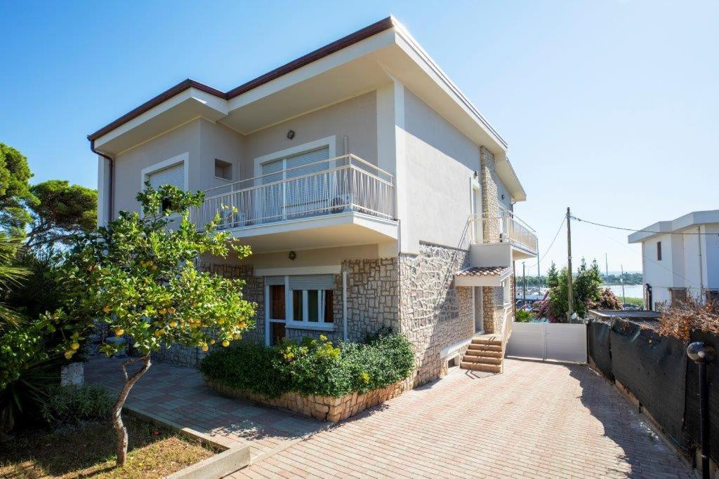una casa bianca con balcone e passerella di Appartamento 150 mq in villa sul mare a Fertilia a Fertilia