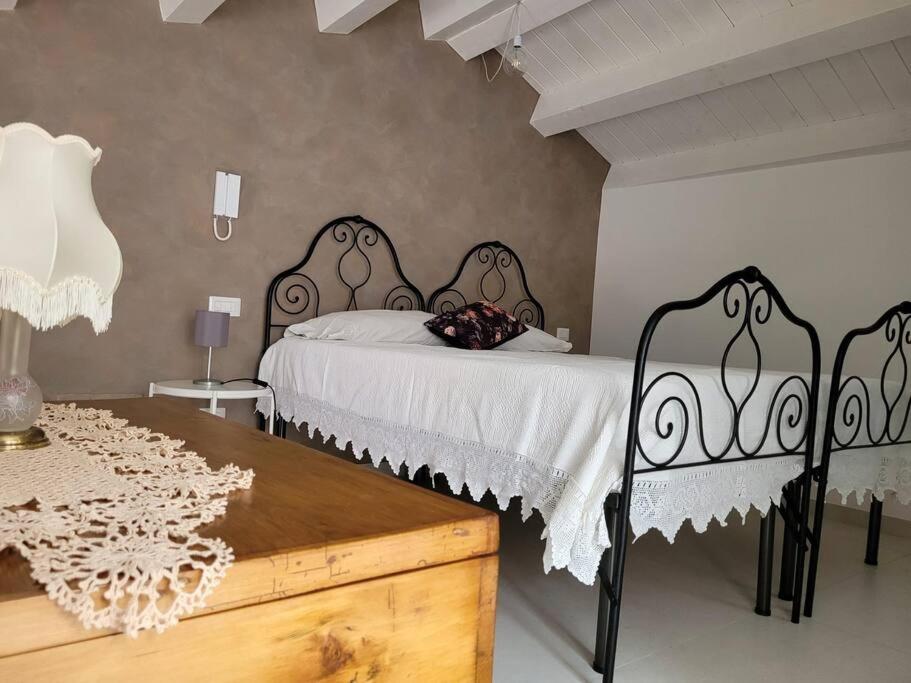 a bedroom with two beds with white sheets and a table at A 2 passi dal centro in Palazzolo Acreide