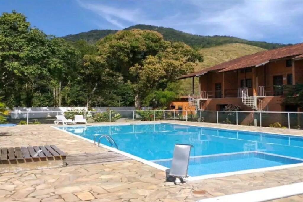 uma piscina de resort com uma montanha ao fundo em MARA Maranduba! Apê c/ Piscina. em Ubatuba