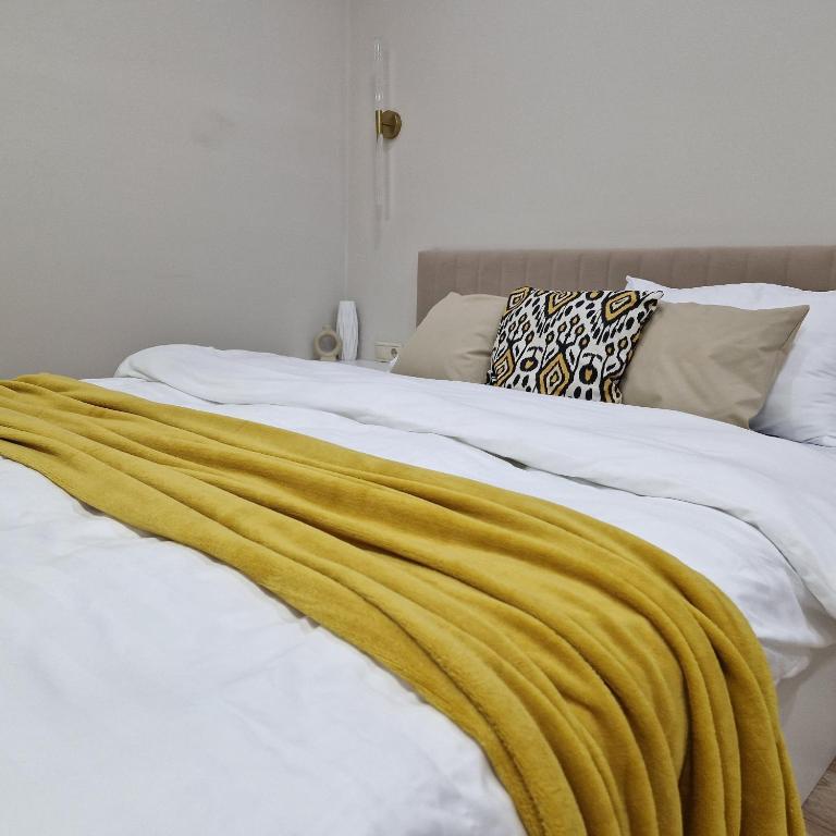 uma cama com um cobertor amarelo em cima em Однокомнатная квартира студия Мега Парк em Almaty