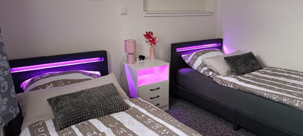 2 Betten in einem Zimmer mit lila Leuchten in der Unterkunft Ferienwohnung Auetal 
