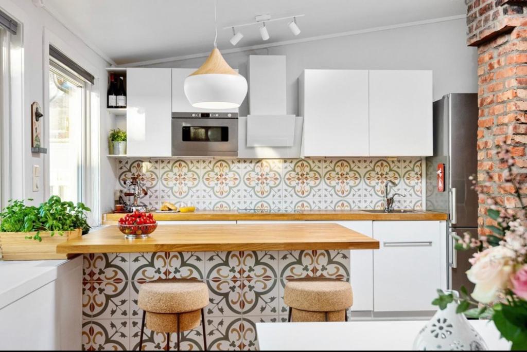 a kitchen with white cabinets and a counter with stools at Penthouse in Oslo's hippest district Grünerløkka in Oslo