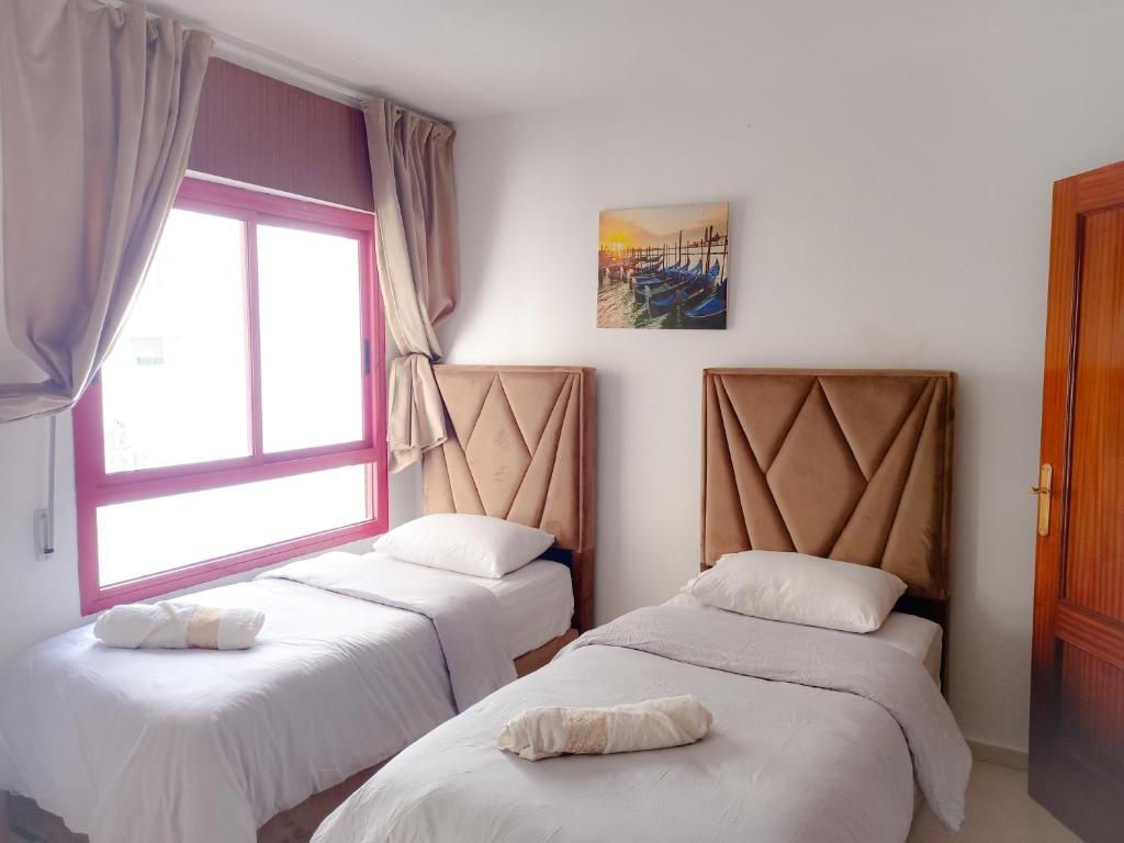 three beds in a room with a window at Amazing Appartement au centre ville en face HILTON & Gare Train de TGV de TANGER in Tangier