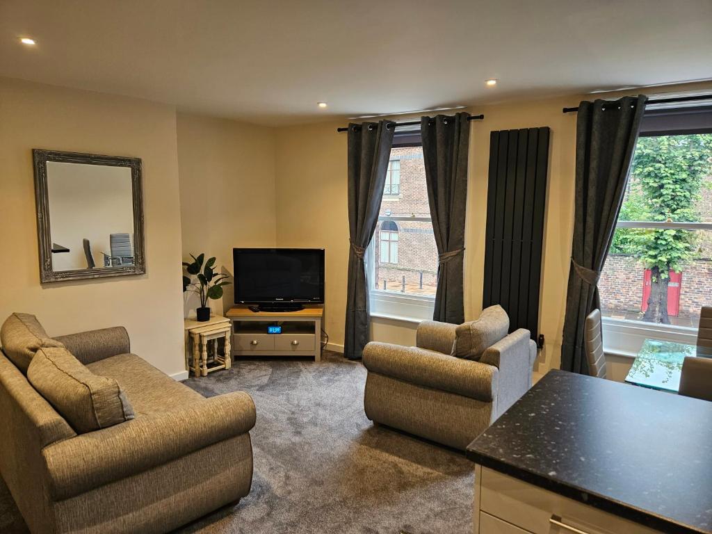 a living room with two chairs and a flat screen tv at Carlisle City Centre. The Foremans Residence. in Carlisle