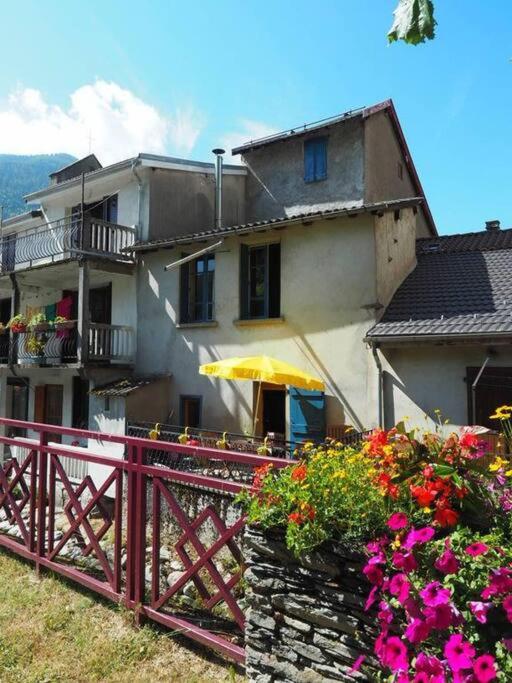 une maison avec une clôture et des fleurs devant elle dans l'établissement Chaleureuse maison en pierres avec terrasse, à Auzat