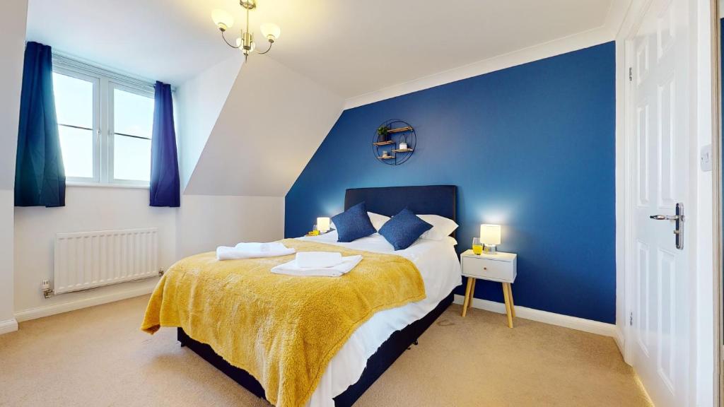 a blue bedroom with a bed and a blue wall at Duxford Deluxe 