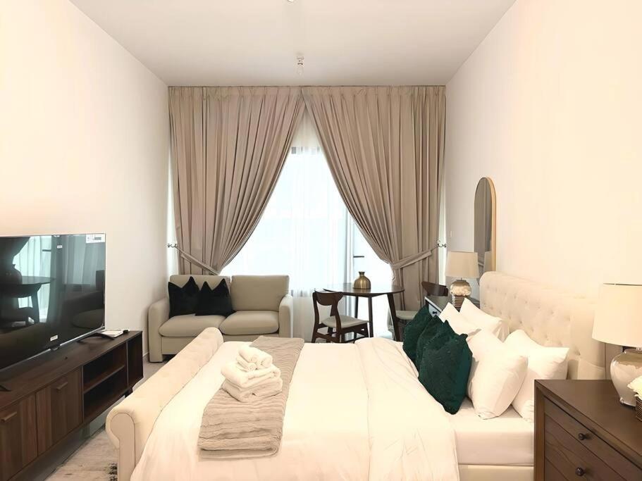 a white bedroom with a large bed and a couch at Classy Studio in Masdar City in Al Qurayyah