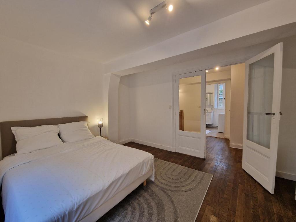 a bedroom with a large white bed and a hallway at Centre Historique LAVAL in Laval