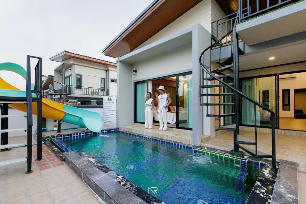 two people standing in front of a house with a pool at Sichon Pool Villa - สิชลพูลวิลล่า 