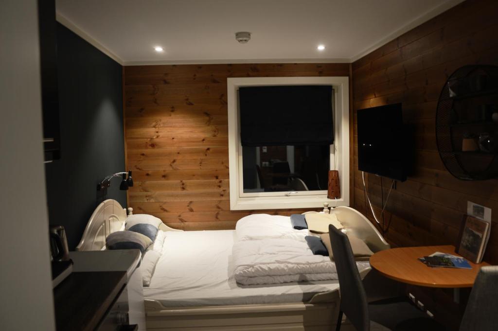 Fossheim Lodge - arealeffektiv minileilighet في Torset: غرفة نوم بسرير ونافذة وطاولة