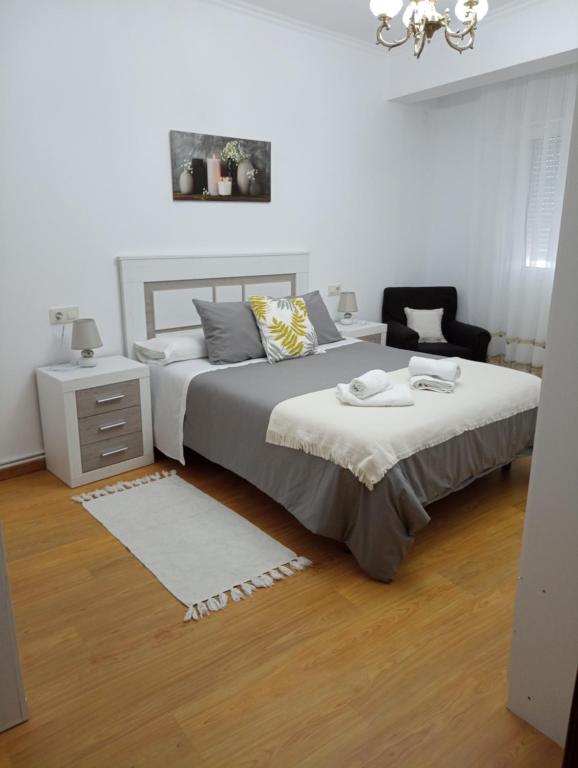 a white bedroom with two beds and a night stand at Casa Jesús in Muxia