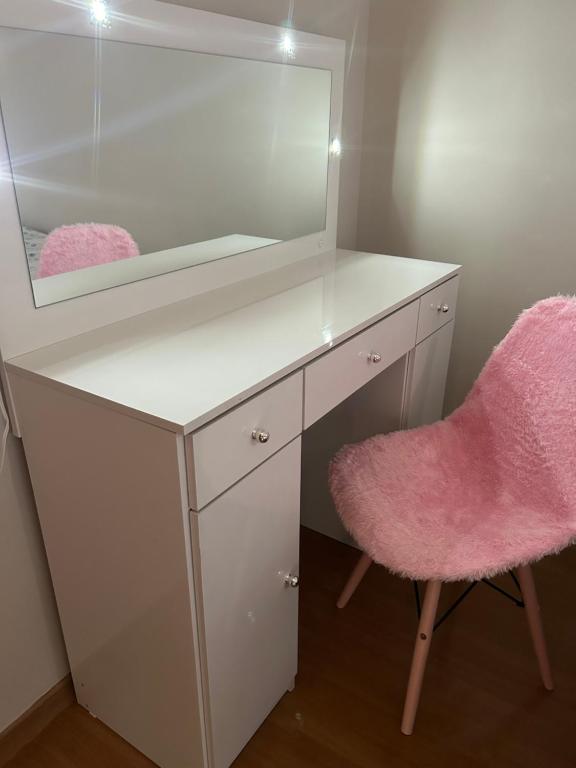 a white desk with a mirror and a pink chair at Apartamento ACOMODA 5 PESSOAS próximo ao Uberlândia Shopping in Uberlândia