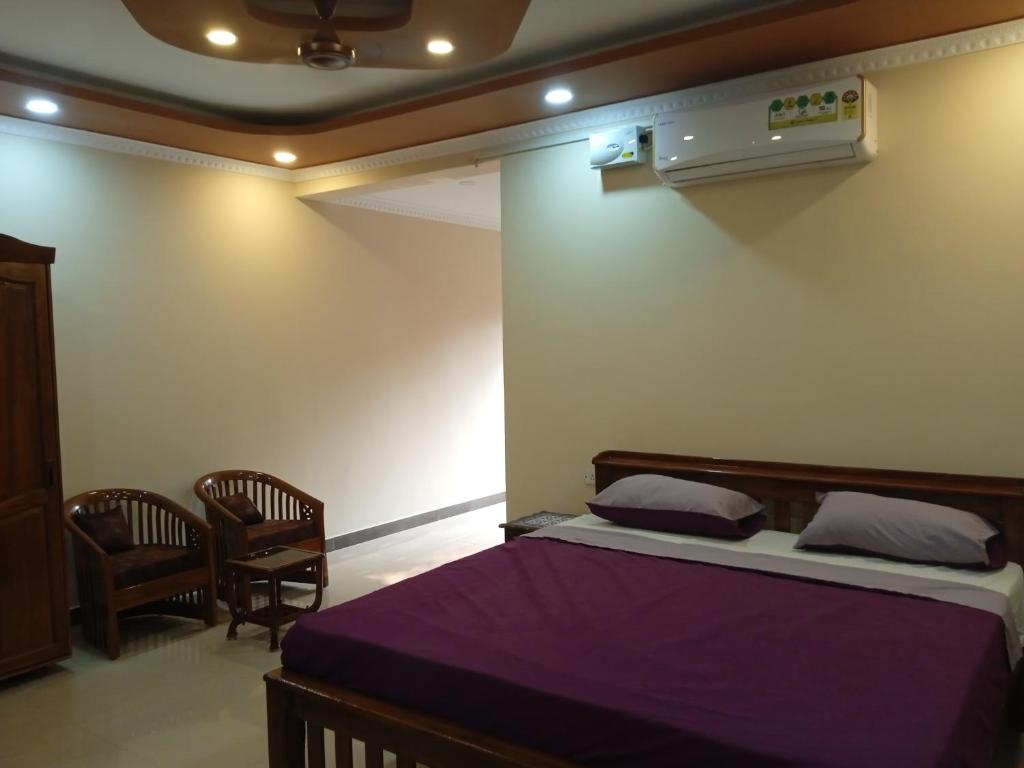 una camera da letto con un letto con lenzuola viola e due sedie di Casa Coutinho ad Alto Porvorim