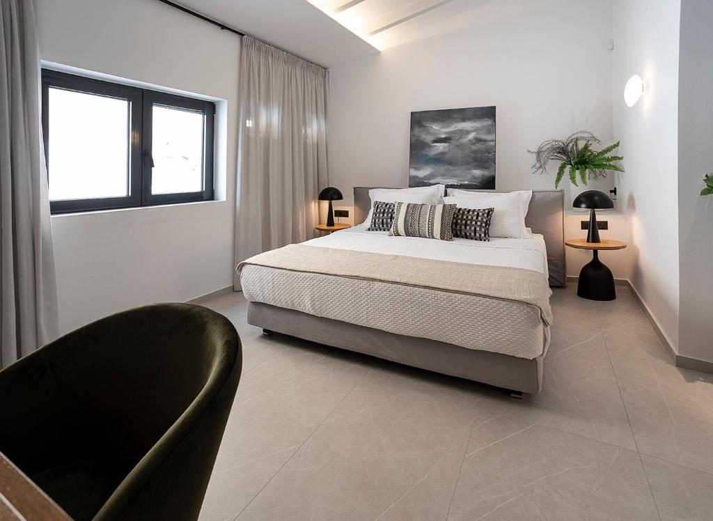 a white bedroom with a bed and a chair at New Villa In Downtown in Athens