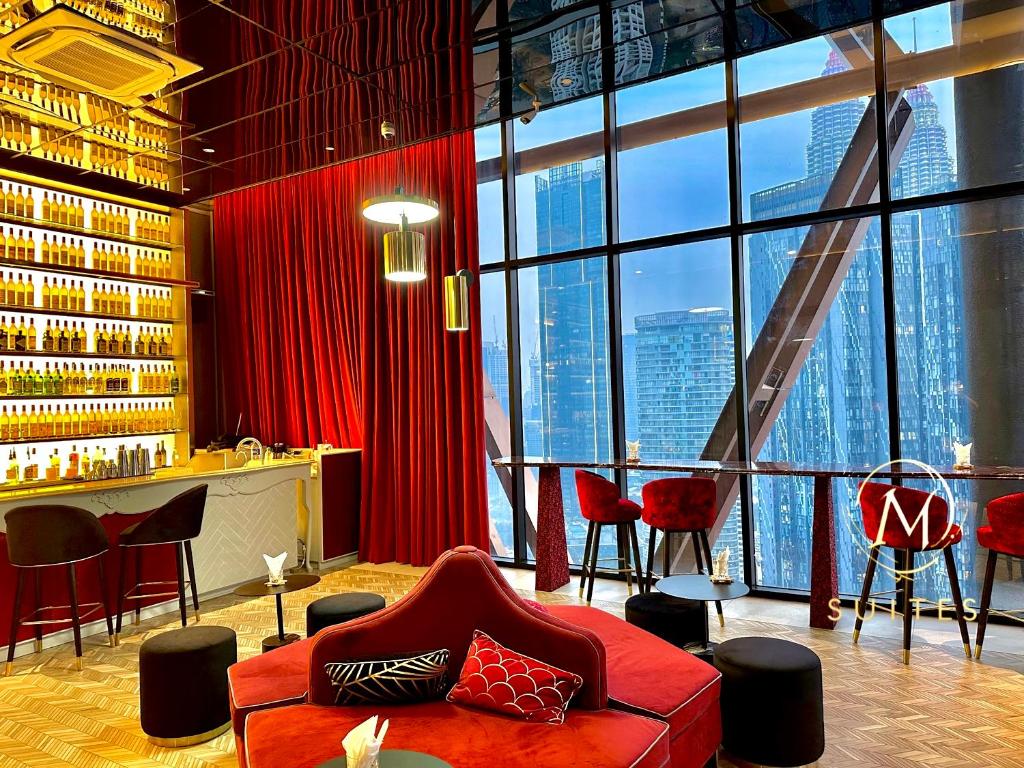 a room with a red couch and a bar with windows at Scarletz Suites KLCC by M Suites in Kuala Lumpur