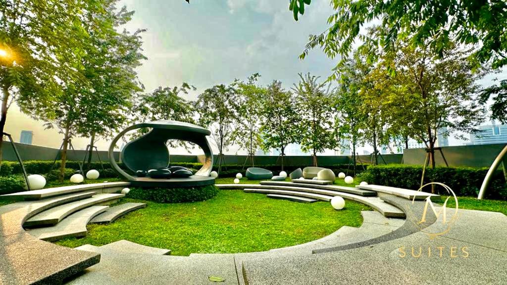 a garden with a bench and chairs and grass at Scarletz Suites KLCC by M Suites in Kuala Lumpur