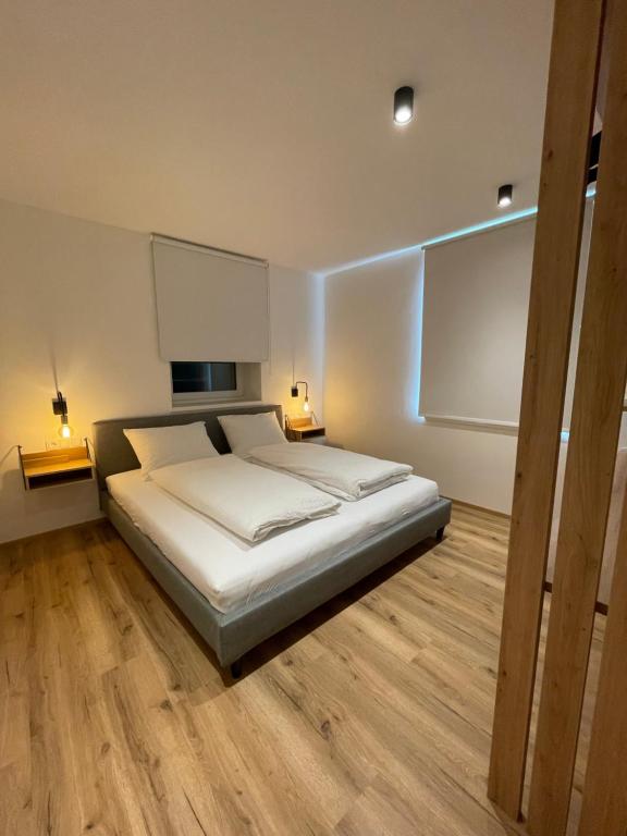 a bedroom with a bed with white sheets and wood floors at Amontis Dolomites in Siusi