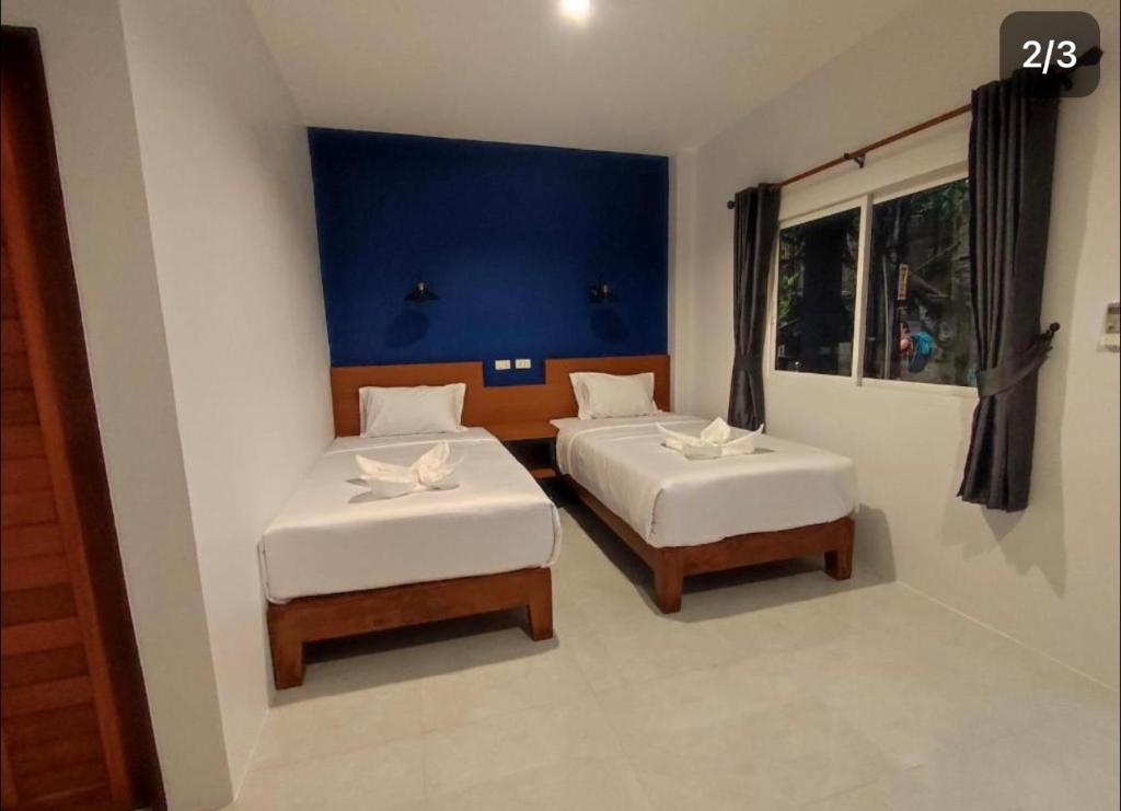 a bedroom with two beds and a blue wall at PP. Valentine Bungalow in Phi Phi Don