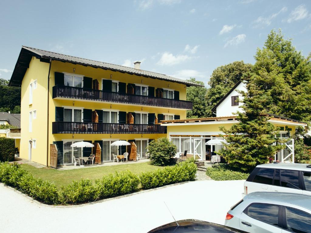 un edificio amarillo con coches estacionados frente a él en Pension Regia, en Velden am Wörthersee