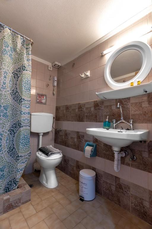 a bathroom with a sink and a toilet and a mirror at Sappho Hotel in Skala Eresou