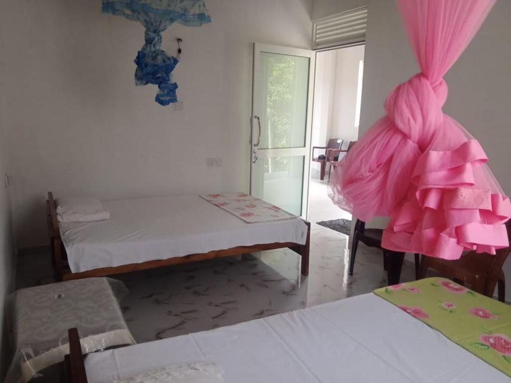 Cette chambre comprend 2 lits et des rideaux roses. dans l'établissement Kandyan Guest house, à Kandy