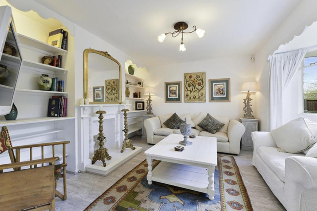 a living room with white furniture and a mirror at Pass the Keys Bright Cosy Cottage in Esher, West End in Esher