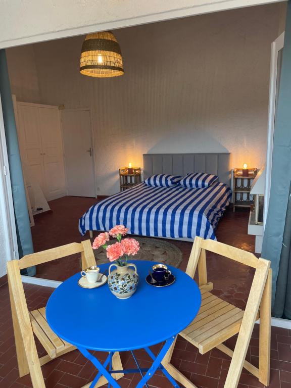 Una habitación con una mesa y sillas azules y una cama en Sole Mio, T2 avec loggia et petit aperçu mer, en Bormes-les-Mimosas