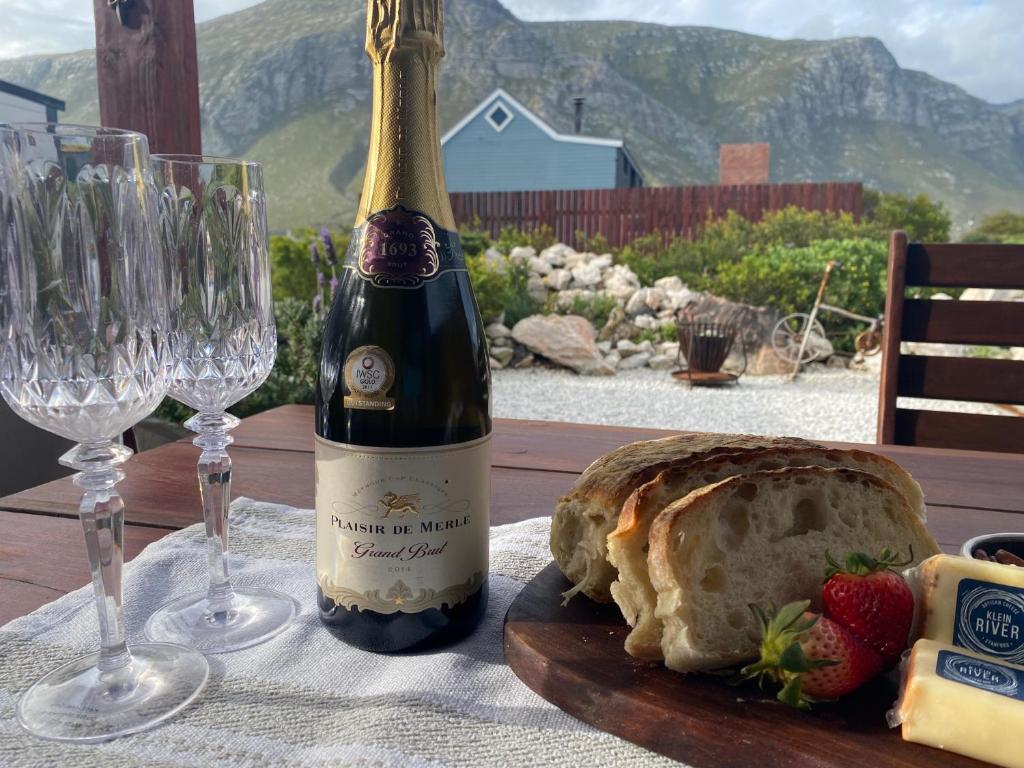 a bottle of wine and a loaf of bread and wine glasses at Hidden Stream Cottage in Bettyʼs Bay